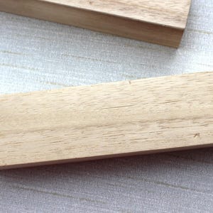Peut inclure: Deux blocs de bois rectangulaires de couleur brun clair sont présentés. Le grain du bois est visible sur la surface. Les blocs sont posés sur une surface texturée de couleur claire.