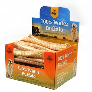 May include: A cardboard box filled with natural water buffalo pet treats. The box is orange and white with the text "100% Water Buffalo" and images of dogs. The treats are long, light brown, and cylindrical.