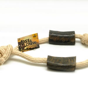 May include: A beige rope dog toy with two brown rubber chew ends. The rope is knotted and the ends are shaped like horns. The toy is labeled "Toss & Chew" with the text "A Super Buffalo Chew".