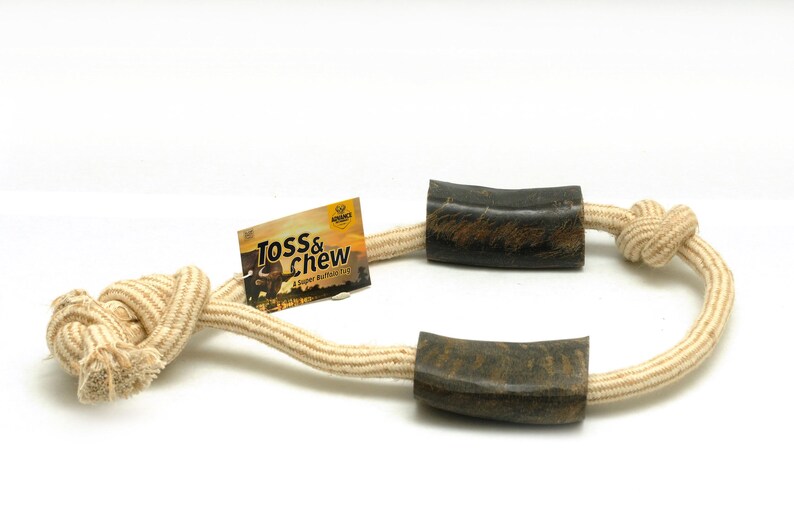 May include: A beige rope dog toy with two brown rubber chew ends. The rope is knotted and the ends are shaped like horns. The toy is labeled "Toss & Chew" with the text "A Super Buffalo Chew".