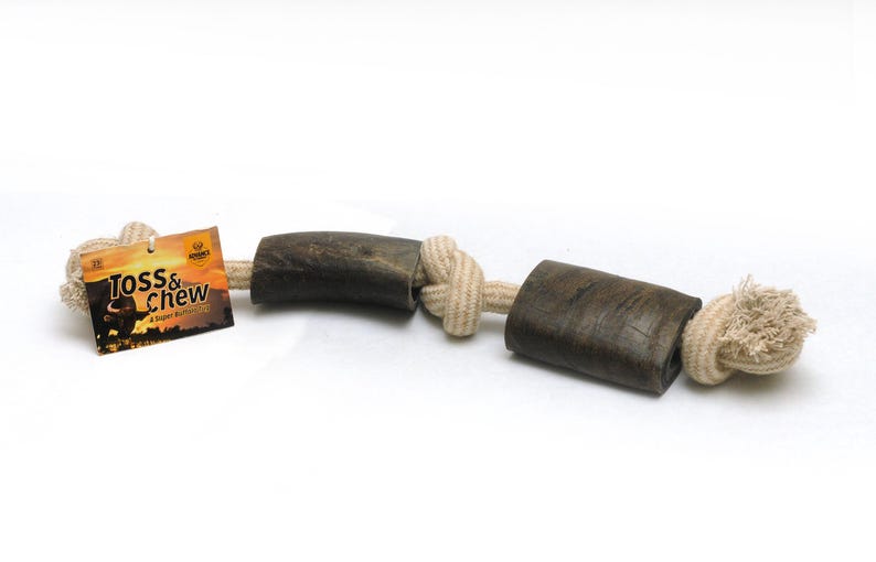 May include: A brown antler dog chew toy with a natural rope attached. The toy is tied in a knot and has the words "Toss & Chew" on the label.
