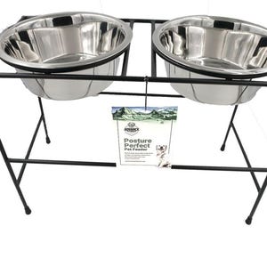 May include: A black metal pet feeder with two stainless steel bowls. The bowls are elevated on a rectangular frame with four legs. A tag with the words "Posture Perfect Pet Feeder" hangs between the bowls.