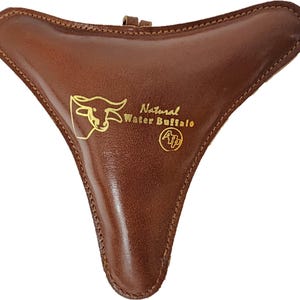May include: A brown leather ocarina with a gold design of a water buffalo and the text "Natural Water Buffalo" and "A/P".