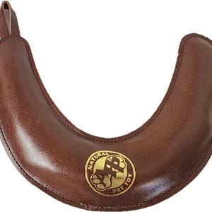 May include: Brown leather dog chew toy shaped like a horseshoe with a gold logo that says "Natural Pet Toy".