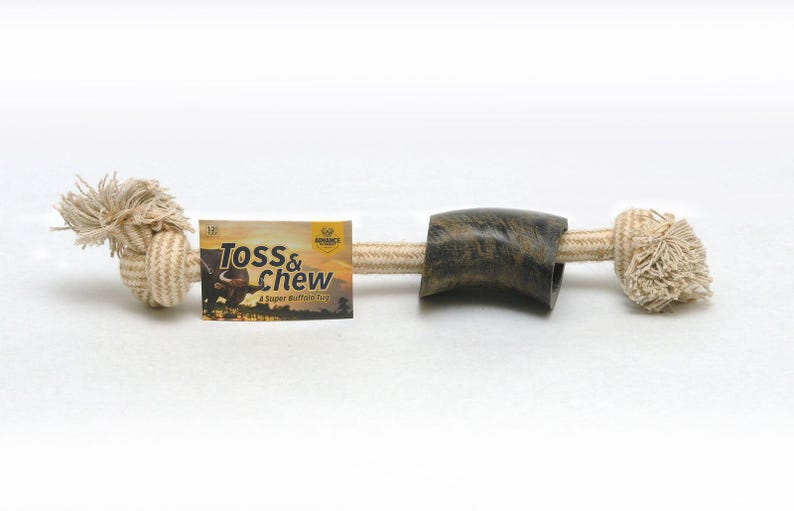 May include: A natural rope dog toy with a brown and green buffalo horn in the center. The rope is knotted at both ends and the toy is labeled "Toss & Chew - A Super Buffalo Toy".