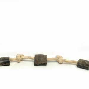 May include: A beige rope dog toy with three brown rubber chew toys attached. The rope is knotted between each chew toy. The toy has a label that says "Toss & Chew".