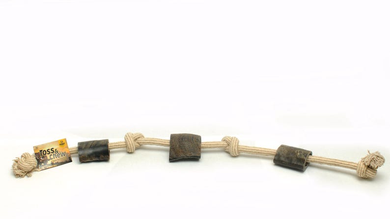 May include: A beige rope dog toy with three brown rubber chew toys attached. The rope is knotted between each chew toy. The toy has a label that says "Toss & Chew".