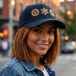 May include: Navy blue baseball cap featuring gold-colored sun, turtle, and flower designs. The cap has a curved brim and is made of a soft material. This hat is a stylish accessory for everyday wear.