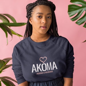 May include: A navy blue sweatshirt with a white graphic that says "AKOMA" with a pink heart above the word and the text "PATIENCE & TOLERANCE" below the word.