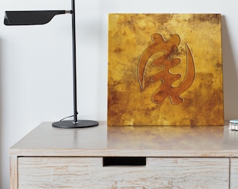 May include: A gold-toned canvas print featuring a brown Adinkra symbol, the Sankofa, on a textured background.