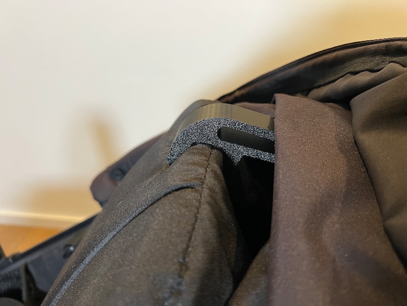 May include: A black plastic hook with a textured surface attached to a black fabric bag.