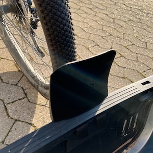 Puede incluir: Guardabarros de bicicleta negro con una superficie texturizada. El guardabarros est&aacute; unido a un cuadro de bicicleta negro.