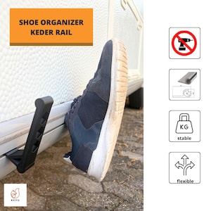 Op de afbeelding: Een zwarte kunststof schoenenorganizer kederrailhaak bevestigd aan de buitenkant van een wit voertuig. Een donkerblauwe sneaker rust tegen de haak. De afbeelding bevat iconen voor boren niet nodig, een kederrailprofiel, stabiliteit en flexibiliteit.