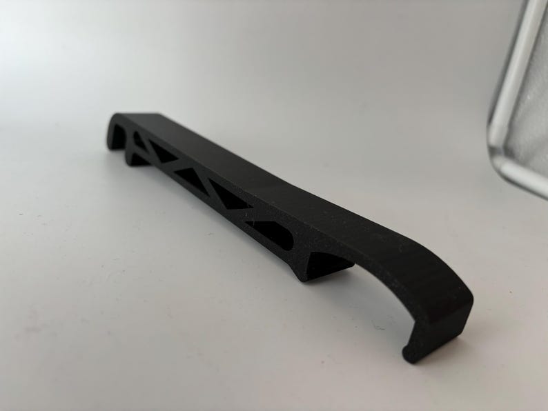 May include: A black plastic bottle opener with a unique geometric design. The opener has a curved handle and a sharp edge for opening bottles.