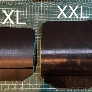 Puede incluir: Dos piezas rectangulares negras, flexibles y texturizadas, etiquetadas como "XL" y "XXL", sobre una estera de corte verde. Las piezas est&aacute;n hechas de un material texturizado y tienen bordes redondeados.