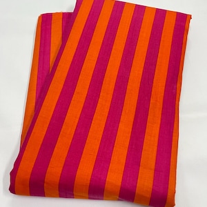 May include: A folded fabric with bold vertical stripes in alternating shades of orange and fuchsia. The fabric appears to be a lightweight material, possibly cotton or linen, with a slight sheen. The stripes are evenly spaced and create a vibrant, eye-catching pattern.
