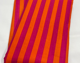 Puede incluir: Tela doblada con rayas verticales en naranja y fucsia. Las rayas alternas crean un patrón dinámico. La tela parece ligera, posiblemente de algodón o lino, con un ligero brillo. Ideal para confección de ropa o decoración del hogar.