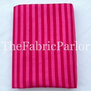 Puede incluir: Una pieza de tela doblada que presenta un patr&oacute;n de rayas verticales en tonos alternos de magenta brillante y rosa fucsia intenso. El texto TheFabricParlor est&aacute; superpuesto en blanco en el centro de la tela, que tiene una textura lisa.