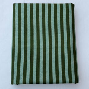 May include: A rectangular piece of fabric featuring a repeating vertical striped pattern. The design consists of alternating stripes in a deep forest green and a lighter, muted sage green color, creating a consistent and uniform striped textile.