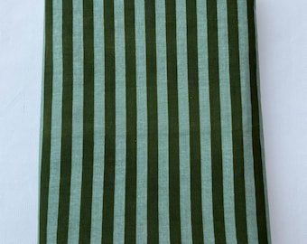 Puede incluir: Una pieza de tela rectangular que presenta un patrón de rayas verticales repetitivas. El diseño consiste en rayas alternas en un verde bosque profundo y un verde salvia más claro y apagado, creando un textil a rayas uniforme.