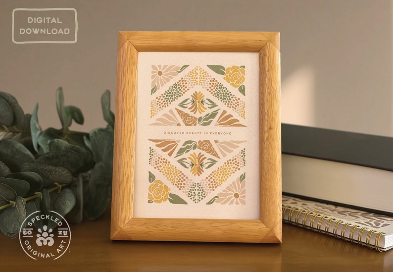 May include: A framed print with a geometric design featuring flowers in shades of green, yellow, and brown. The print has the text "Discover beauty in everyone" in the center.
