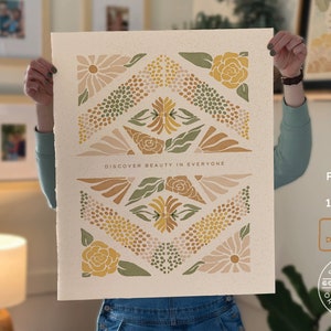 May include: A digital art print featuring a geometric pattern of flowers in shades of yellow, green, and pink. The print has the text "DISCOVER BEAUTY IN EVERYONE" at the bottom and is available in sizes up to 16 inches by 20 inches.
