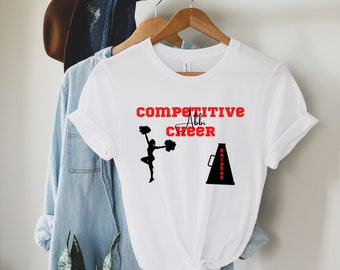 Peut inclure: T-shirt blanc avec du texte rouge qui dit "COMPETITIVE Abby CHEER" et une silhouette noire d'une pom-pom girl avec des pom-poms. Il y a aussi un mégaphone noir avec le mot "RAIDERS" écrit dessus.