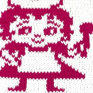 Puede incluir: Un cuadrado tejido blanco con un diseño de ángel de dibujos animados de color magenta. El ángel tiene un halo y sostiene un báculo. Los bordes del cuadrado también son magenta.