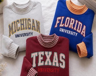 Könnte beinhalten: Drei langärmelige Sweatshirts mit Universitätsnamen. Ein graues Michigan University Sweatshirt mit Vichy-Kragen, ein blaues Florida University Sweatshirt mit orangefarbenem Vichy-Kragen und ein weinrotes Texas University Sweatshirt mit rotem Vichy-Kragen.