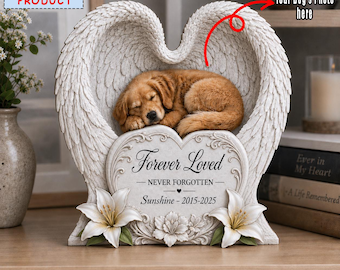 Könnte beinhalten: Eine Gedenktafel mit einem schlafenden goldenen Welpen, der in geformten Engelsflügeln liegt. Das herzförmige Zentrum zeigt den Text Forever Loved, NEVER FORGOTTEN und Sunshine - 2015-2025, akzentuiert durch zwei weiße Lilien an der Basis.