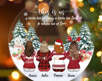 May include: A round clear acrylic Christmas ornament featuring a printed illustration of four people from behind, wearing festive sweaters and reindeer headbands, standing before snowy pine trees and a snowman with the text this is us.