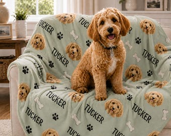Könnte beinhalten: Eine hellgrüne Fleecedecke mit einem sich wiederholenden Muster aus dem Gesicht eines goldenen Hundes, schwarzen Pfotenabdrücken, weißen Knochenformen und dem Namen TUCKER, der in schwarzen Großbuchstaben auf den Stoff gedruckt ist.