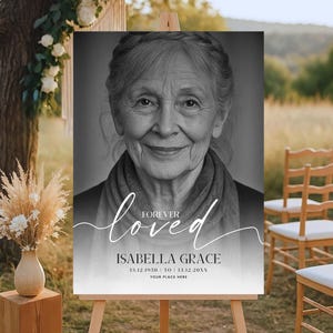 May include: A monochrome memorial sign displayed on an easel. The sign shows a portrait of an elderly woman, with the words "forever loved" and the name "Isabella Grace" in cursive script. The sign includes dates and the phrase "Your Place Here".