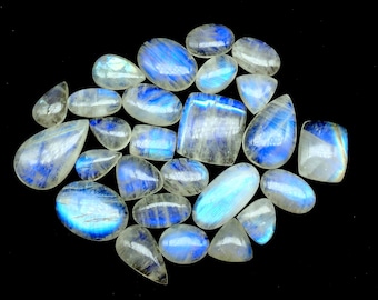 May include: A collection of iridescent moonstone cabochons in various shapes and sizes. The stones are a milky white color with a blue sheen.