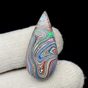 May include: A teardrop-shaped cabochon of colourful agate with swirling patterns of blue, green, red, and brown.
