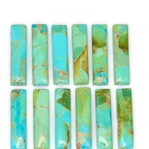 Peut inclure: Douze pierres précieuses rectangulaires en turquoise, avec des nuances de bleu, de vert et de brun. Les pierres sont disposées en trois rangées de quatre, mettant en valeur leurs motifs et textures naturels. Les pierres sont polies et lisses.