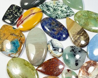 May include: A collection of polished gemstones in various shapes and colors. The assortment includes oval, teardrop, and rectangular stones with patterns of green, blue, yellow, and brown. Some stones have a glossy finish, while others appear more matte.