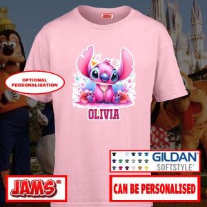 May include: A light pink t-shirt featuring a cartoon character with pink and blue accents, the name "OLIVIA" is printed below the character. The shirt has a crew neck and short sleeves. The shirt is made of Gildan Softstyle material.
