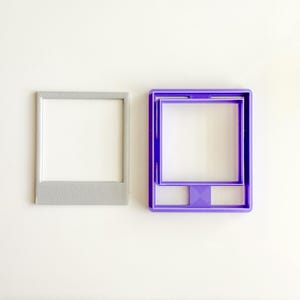 Könnte beinhalten: Zwei quadratische Ausstecher. Einer ist grau, der andere ist lila. Beide haben eine rechteckige Öffnung in der Mitte. Der lila Ausstecher hat ein komplexeres Design mit zusätzlichen geometrischen Formen. Die Ausstecher liegen auf einer weißen Oberfläche.