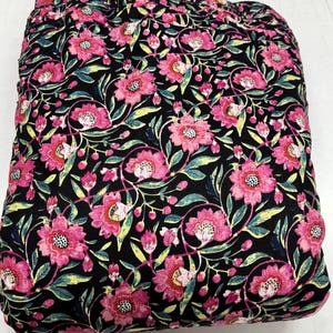 Peut inclure: Tissu noir avec un motif floral rose. Le tissu est plié en deux et le motif est visible des deux côtés.