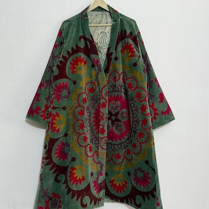 Peut inclure: Longue veste en velours vert à devant ouvert, ornée d'un motif floral vif rouge, jaune et rose. La veste est suspendue à un cintre en bois. La doublure intérieure présente un motif cachemire. Mesure environ 120 cm de long.
