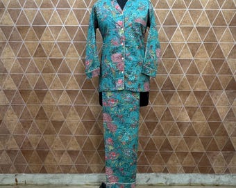 Könnte beinhalten: Türkisfarbenes Pyjama-Set mit Blumen- und Vogelmuster. Das langärmlige Oberteil hat einen Reverskragen und weiße Paspeln. Die passende Hose ist lang und gerade geschnitten. Das Set wird auf einer Schaufensterpuppe präsentiert.