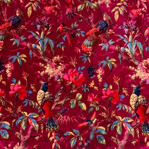 May include: A vibrant red fabric featuring a detailed floral and bird pattern. The design includes colorful birds perched on branches amidst large red flowers, green and blue leaves, and clusters of berries. The overall aesthetic is reminiscent of a vintage botanical print.