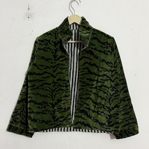May include: A long-sleeve jacket featuring a green and black tiger stripe pattern on the exterior. The interior lining is visible along the front opening, displaying a black and white vertical pinstripe pattern. The jacket has a collar.