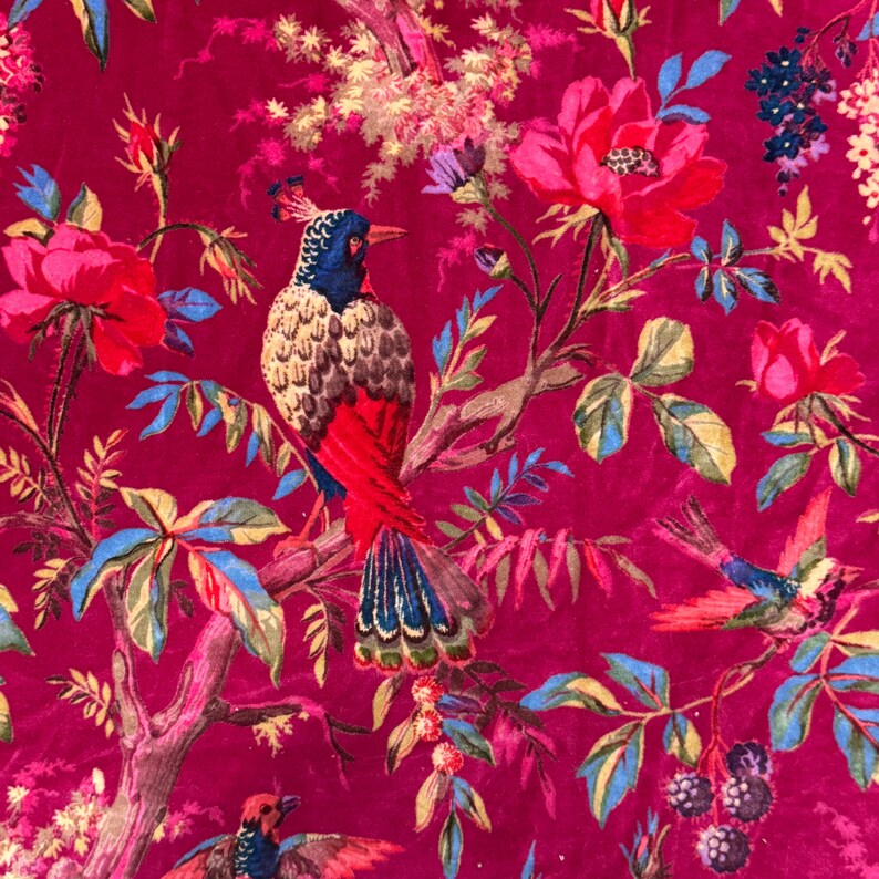 May include: A vibrant fabric featuring a detailed floral and bird pattern. The design showcases colorful birds perched on branches amidst large pink roses, blue and green leaves, and other flowers, all set against a deep magenta background.