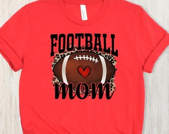 Op de afbeelding: Rood t-shirt met de tekst "FOOTBALL MOM" in zwarte blokletters. Het ontwerp toont een voetbal met een hart en luipaardprint. Het shirt is gemaakt van zacht materiaal.