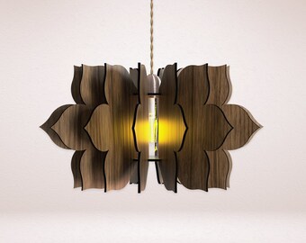 May include: A wooden pendant light fixture with a geometric design resembling a flower. The light is on and emits a warm yellow glow.