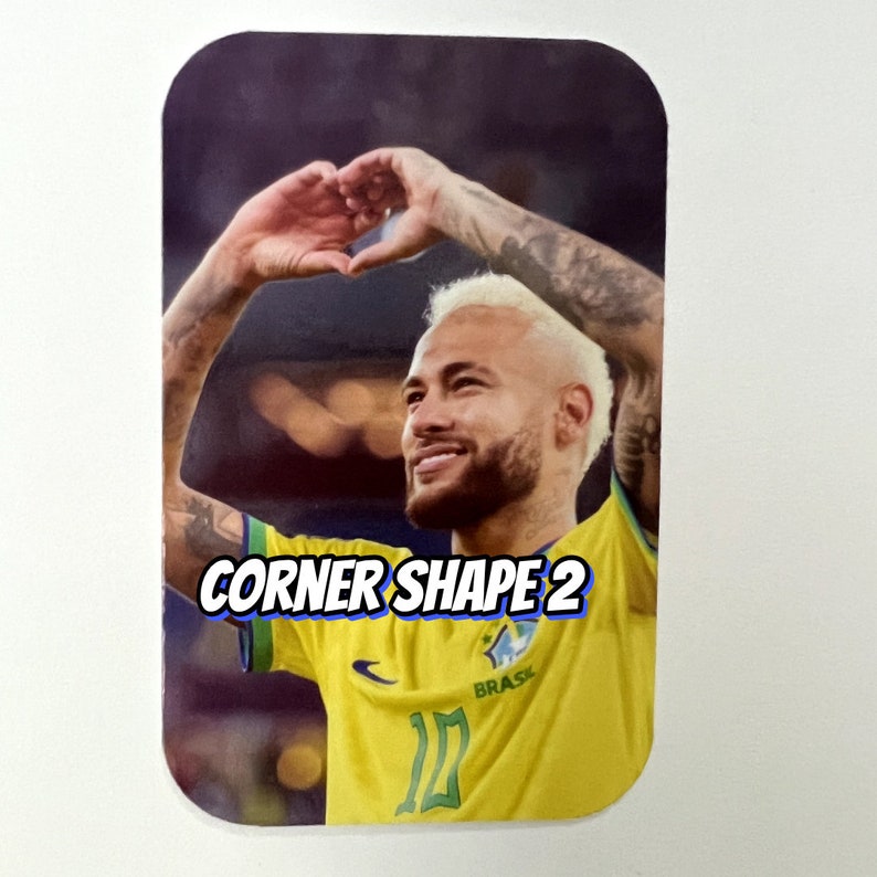 Pu&ograve; includere: Primo piano di un calciatore che indossa una maglia gialla e verde con la scritta "BRASIL" su di essa. Il calciatore sta formando un cuore con le mani e sorride. Il testo "CORNER SHAPE 2" &egrave; visibile nell'immagine.