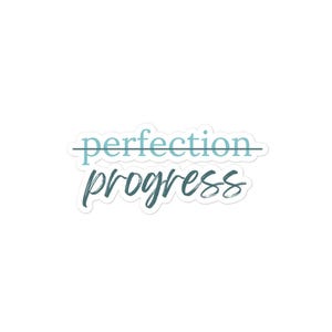 Op de afbeelding: Een sticker met de tekst "perfection" doorgestreept en de tekst "progress" eronder geschreven in een cursief lettertype. De tekst is in tinten blauw en grijs.