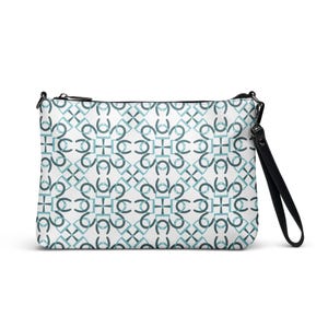 Puede incluir: Un bolso de mano rectangular con fondo blanco y un patrón geométrico turquesa. El bolso tiene una cremallera negra y una correa de muñeca negra. El patrón está formado por formas entrelazadas.